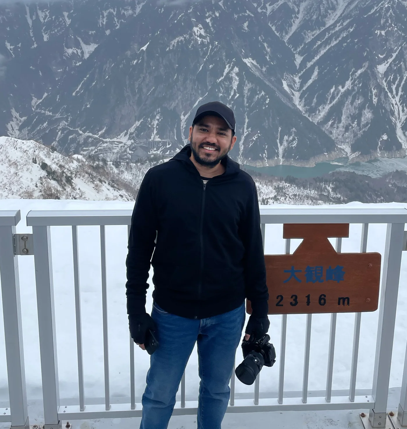 Karan Pawar with a camera in hand at a snowy mountain viewpoint