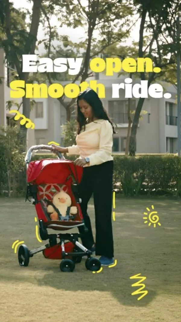 Easy open, smooth ride: a mum strolls through the park with a red foldable stroller.