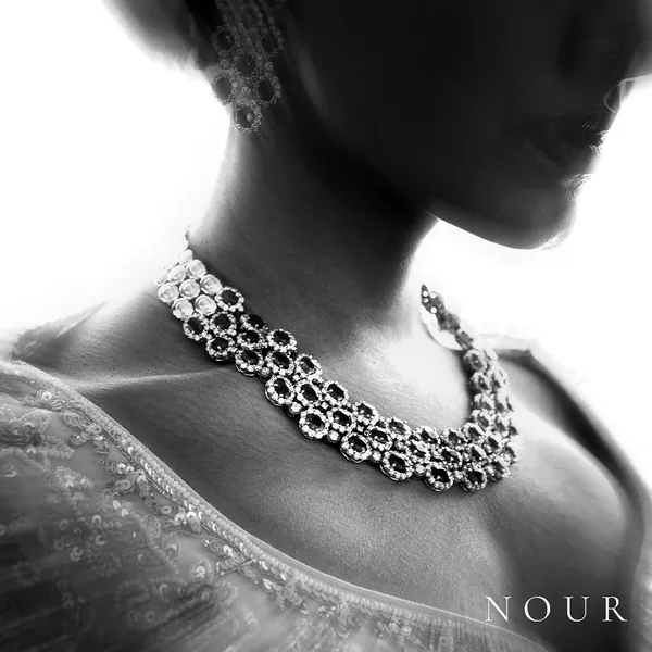 A cluster necklace on a model lit hard against white.