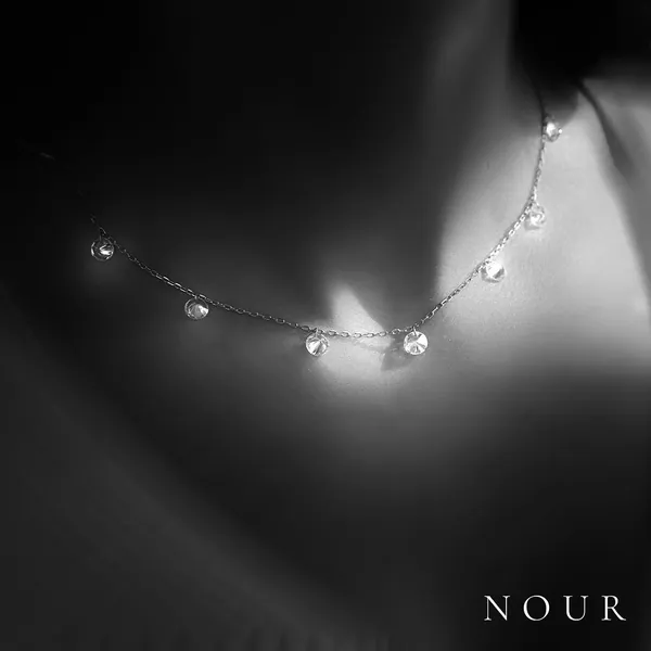 A fine diamond chain glowing on bare skin in the dark.