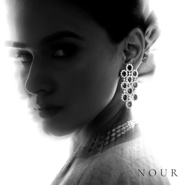 Cluster drop earrings and a choker, the face half lost in shadow.