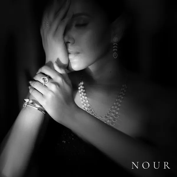 Hands crossed over the face, rings and a bangle catching the light.