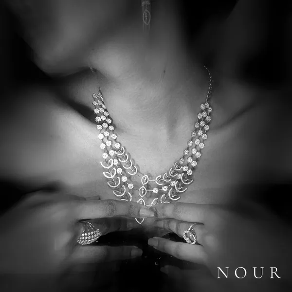 A layered necklace and rings, shot through a blur of movement.