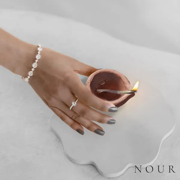 Left panel: a hand in a diamond bracelet carries a diya into frame.