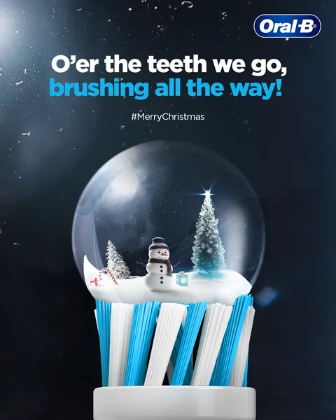 Christmas snow globe with a snowman sits atop a brush head: 'O'er the teeth we go'.