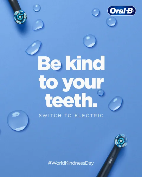 World Kindness Day: two black brushes peek in among water droplets, 'Be kind to your teeth'.