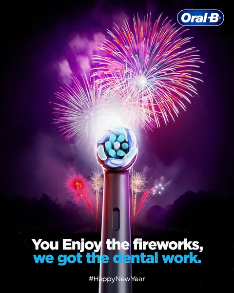 Fireworks burst behind a glowing brush head for New Year: 'we got the dental work'.
