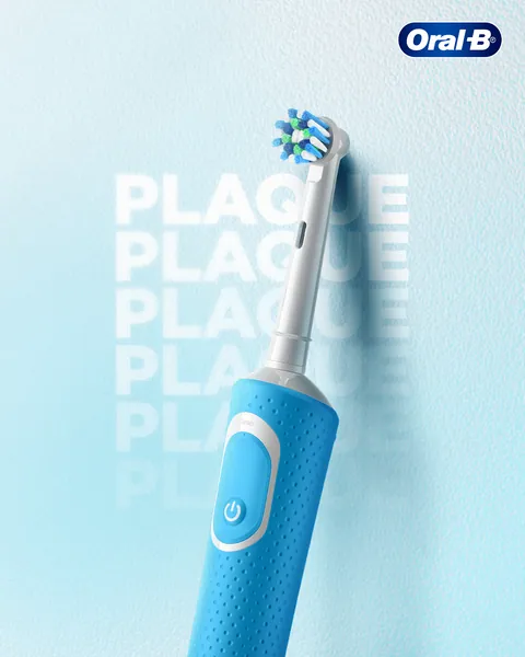 The word plaque, stacked and fading, disappears behind a blue electric toothbrush.