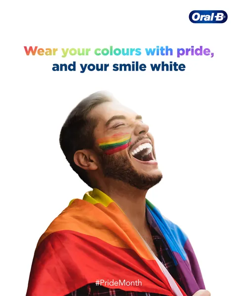 Wrapped in a rainbow flag, face painted, a man laughs: 'Wear your colours with pride'.