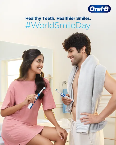 A smiling couple shares a bathroom moment with electric brushes for World Smile Day.
